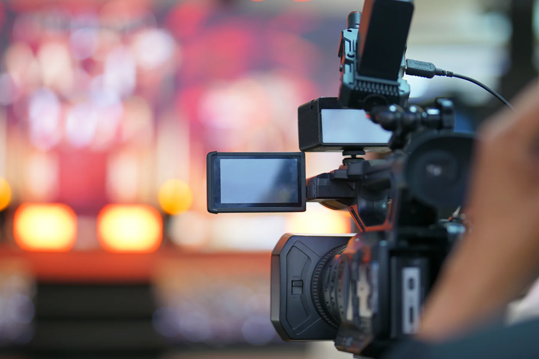 A camera operator filming a lit stage