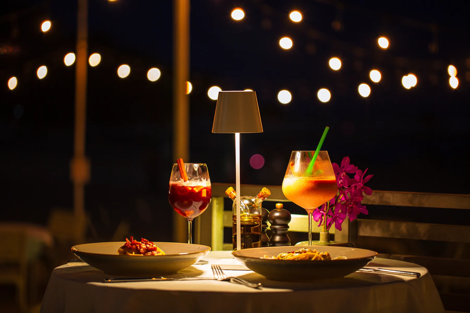 A table set for dinner, with drinks, under warm lights