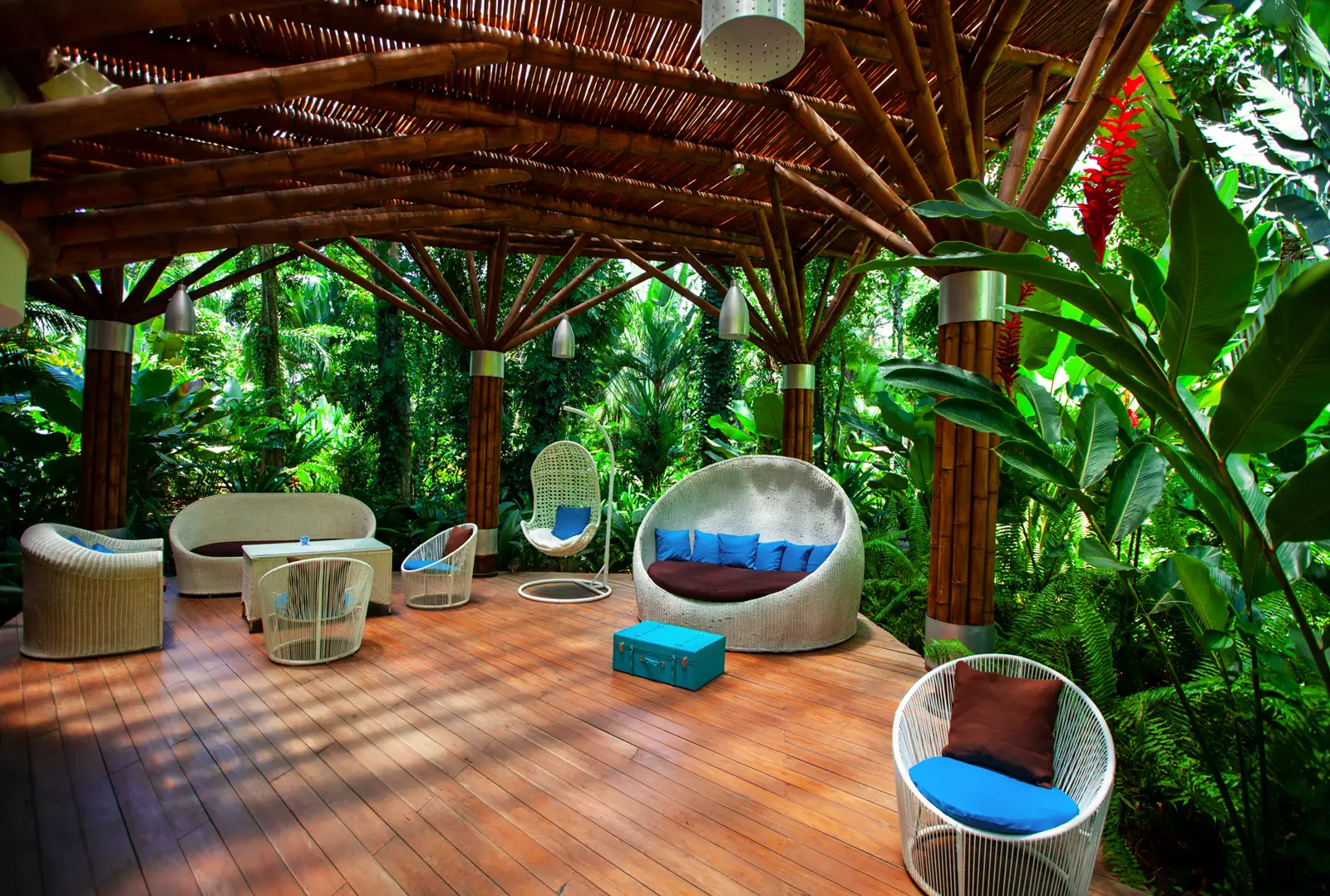 A shaded lounge under a timber roof, set in dense tropical planting